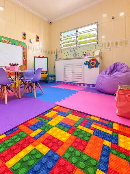 Sala de atendimento com mesa infantil, quadro e piso emborrachado colorido.