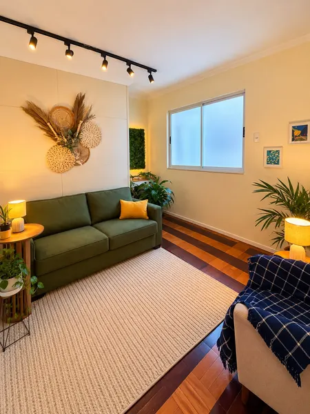 Sala de estar com sofá verde, tapete de fibras e plantas.