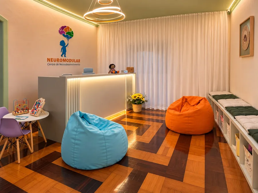 Recepção da Neuromodular, com a logo na parede, puffs coloridos e luz aconchegante.