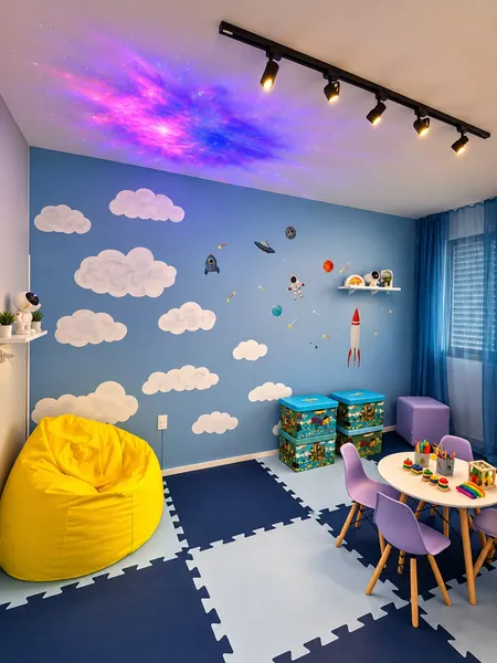 Sala sensorial, com céu de nuvens na parede, projeção de galáxia no teto e puff amarelo.
